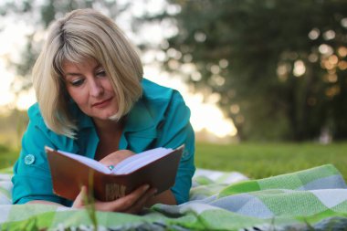 kadınla çimenlerin üzerinde kitapla Park