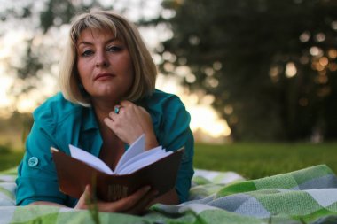 kadınla çimenlerin üzerinde kitapla Park