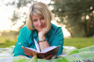 kadınla çimenlerin üzerinde kitapla Park