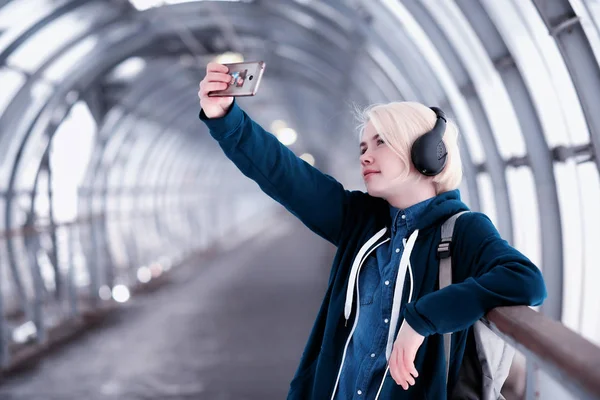 Young student listening to music in big headphones in the subway