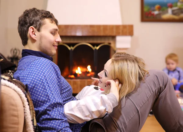 Familie wärmt sich am Kamin auf der Couch — Stockfoto