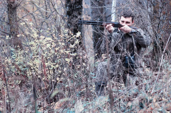 A man in camouflage and with a hunting rifle in a forest on a sp — Stock Photo, Image