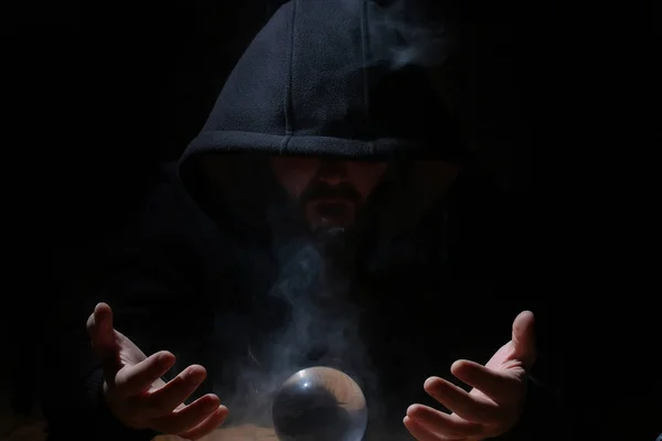 Man in a black hood with cristal ball — Stock Photo, Image