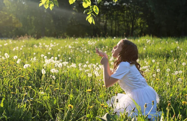 Remaja meniup biji dari bunga dandelion di taman musim semi — Stok Foto