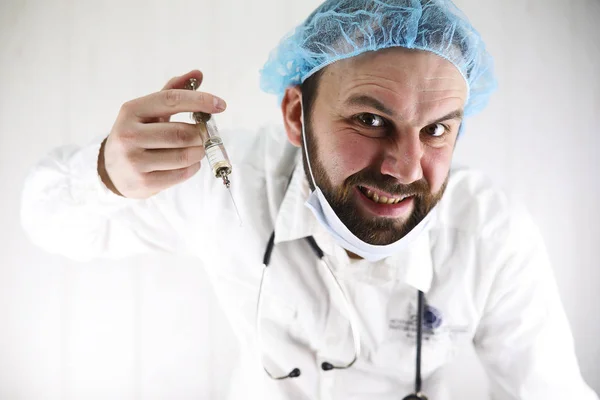 Божевільний бородатий лікар у білому пальто та старому шприці — стокове фото