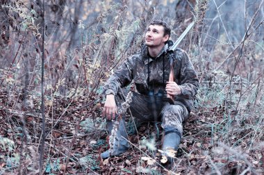 Kamuflaj ve bir sp üzerinde bir ormanda bir av tüfeği ile bir adam