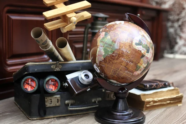 Composition on a wooden floor vintage globe with old leather sui — Stock Photo, Image