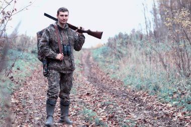 Kamuflaj ve bir sp üzerinde bir ormanda bir av tüfeği ile bir adam