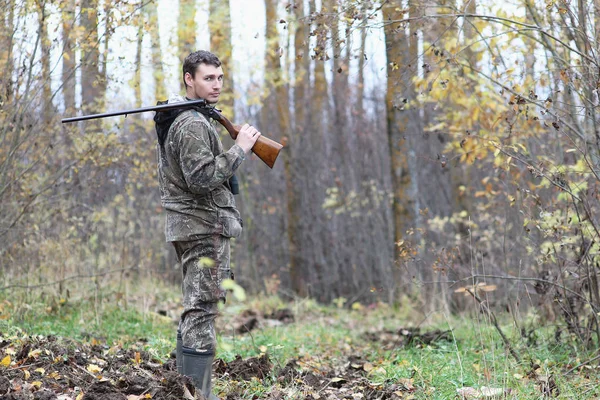 Man in camouflage and with guns in a forest belt on a spring hun