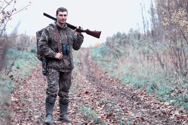 Kamuflaj ve bir sp üzerinde bir ormanda bir av tüfeği ile bir adam