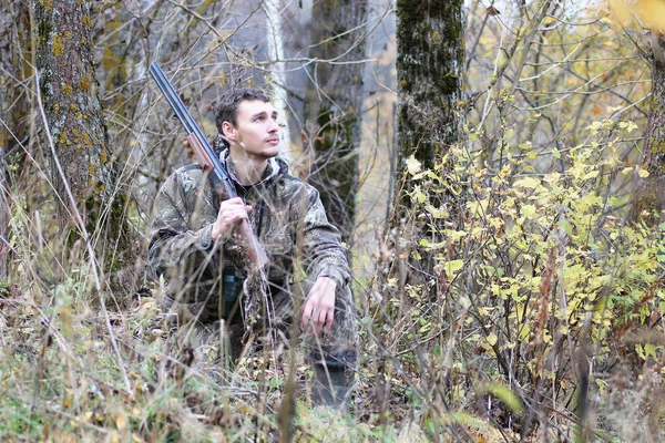 Homem em camuflagem e com armas em um cinto florestal em um hun primavera — Fotografia de Stock