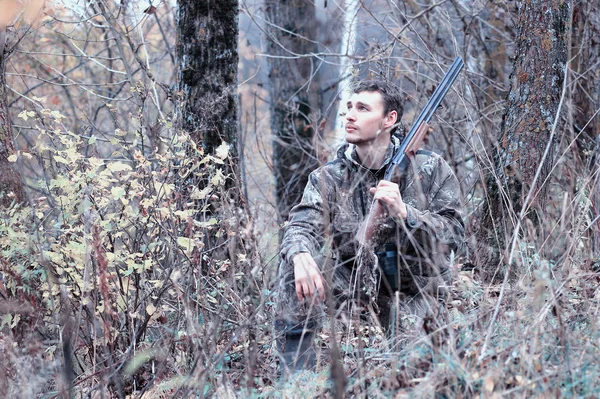 Un hombre en camuflaje y con un rifle de caza en un bosque en una sp —  Fotos de Stock