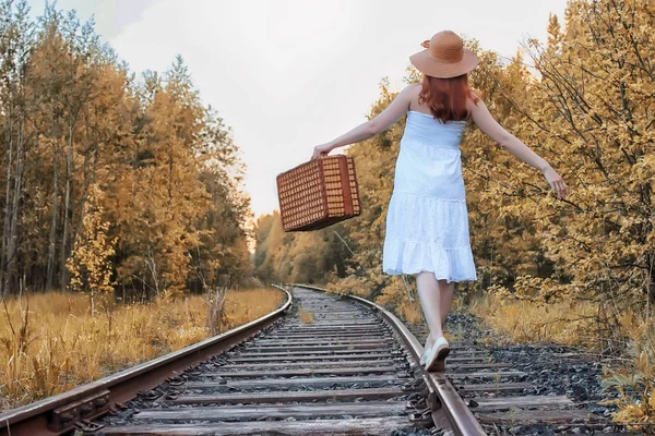 白いサンドレスの秋の公園の女の子とウィッカーのスーツケースが歩く — ストック写真