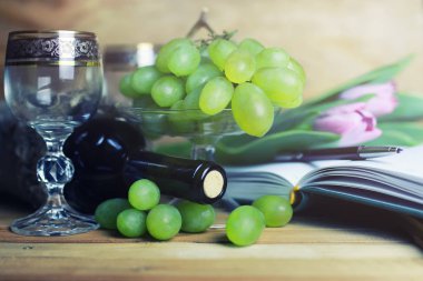 üzüm ve şarap şişesi kitap ile ahşap masa