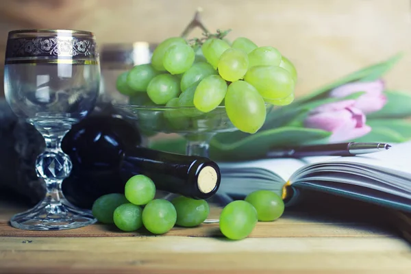 üzüm ve şarap şişesi kitap ile ahşap masa