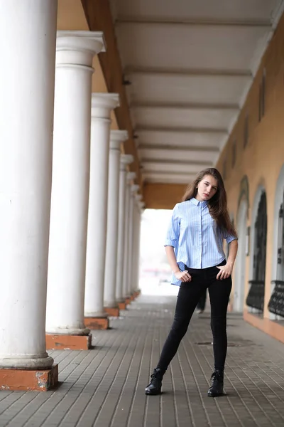 Молодая красивая девушка на прогулке возле здания с колонной — стоковое фото