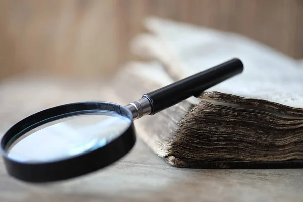 Libros antiguos sobre una mesa de madera y lupa — Foto de Stock