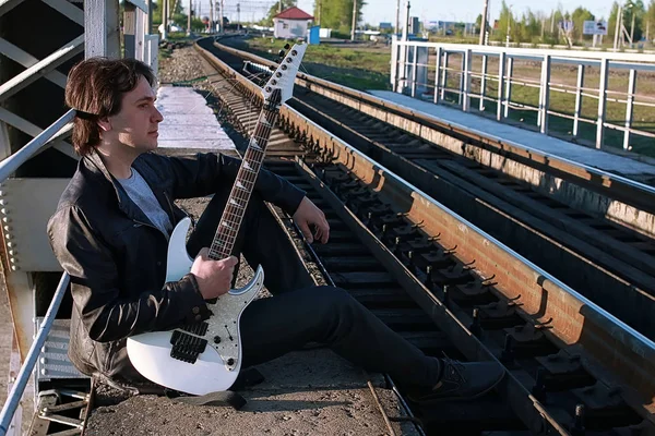 Man met een elektrische gitaar in het industriële landschap buitenshuis — Stockfoto