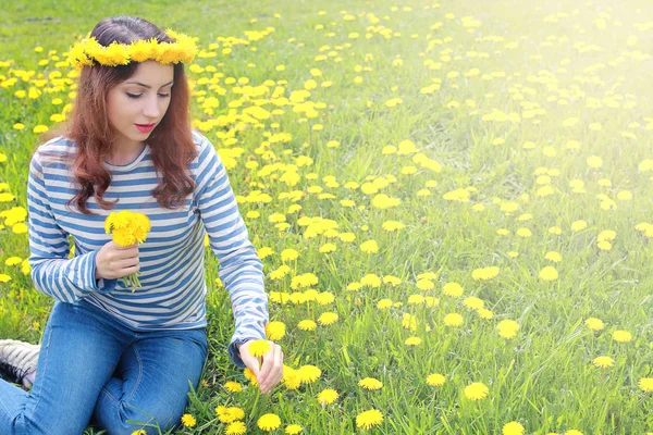 Girl resting on a sunny day in meadow of yellow dandelions — Stock Photo, Image