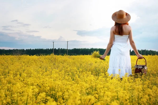 Ragazza in cappello di paglia in un campo di fiori gialli in fiore — Foto Stock