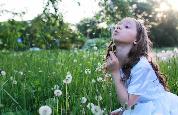 Підліток дме насіння з квітки кульбаби в весняному парку — стокове фото