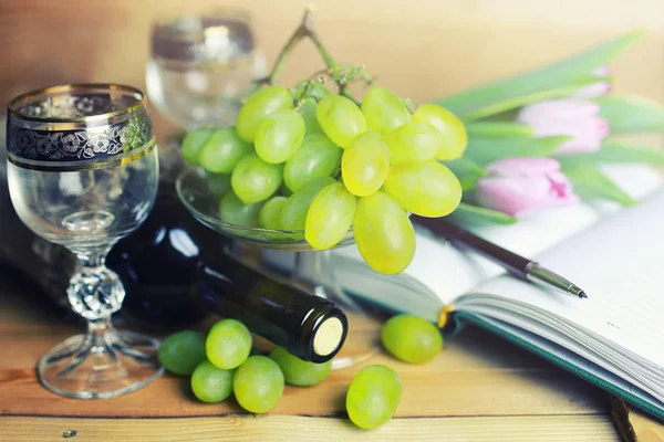 üzüm ve şarap şişesi kitap ile ahşap masa