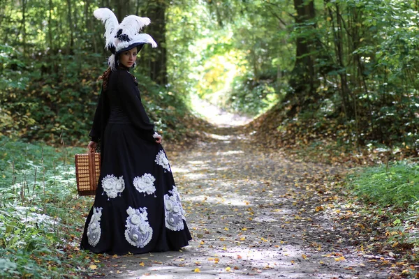 Meisje in de 18e eeuw retro jurk met valise in park — Stockfoto