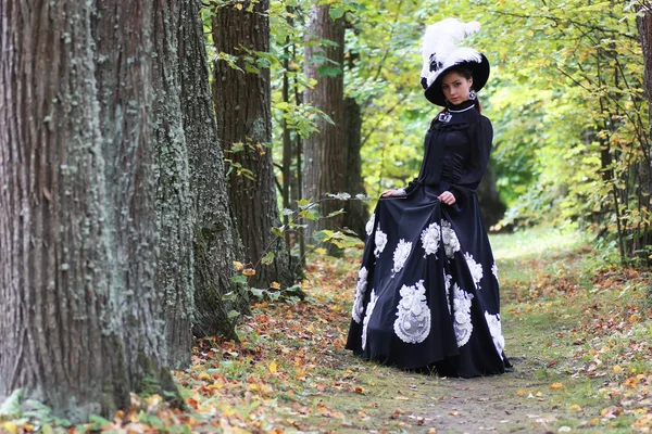 Dame in retro jurk wandelen in bomen steegje — Stockfoto