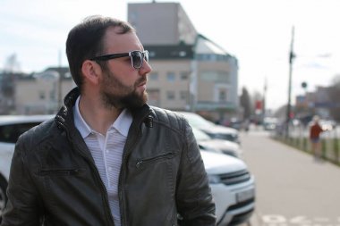 Ceketli ve güneş gözlüklü sakallı adam.