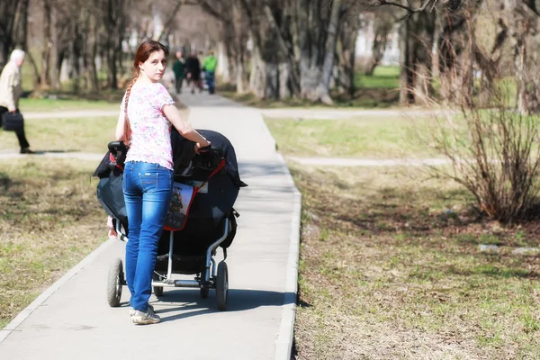 Young mother with stroller in park — Stock Photo, Image