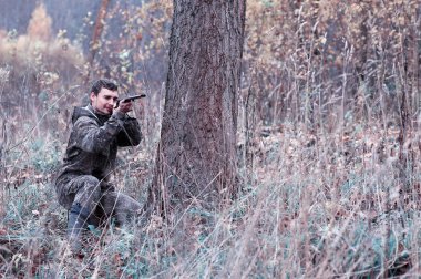 Kamuflaj ve bir sp üzerinde bir ormanda bir av tüfeği ile bir adam