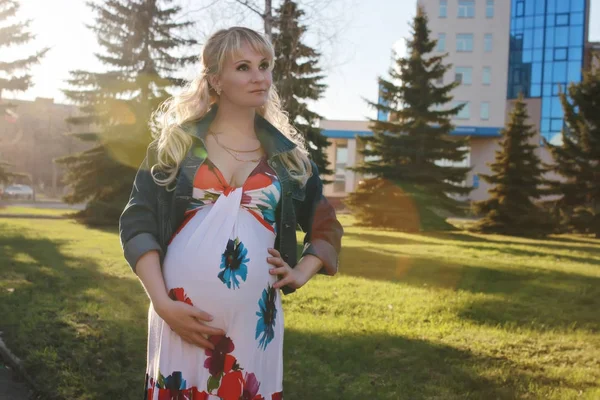 Zwanger meisje loopt rond het stadspark in het voorjaar — Stockfoto