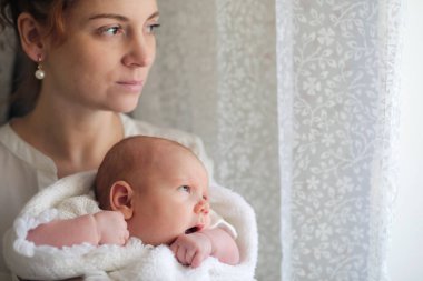 genç anne ve Yenidoğan Bebek kucağında pencerenin kenarında duran