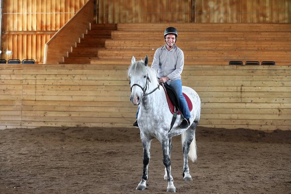 People on a horse training in a wooden arena