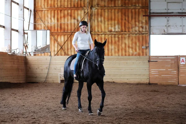 İnsanlar ahşap bir arenada at eğitiminde.