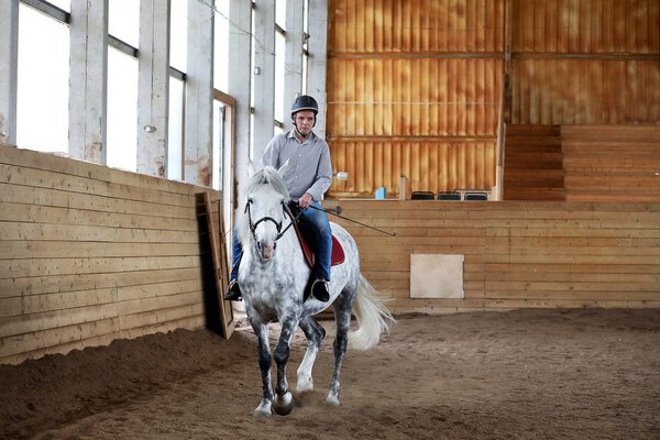 People on a horse training in a wooden arena