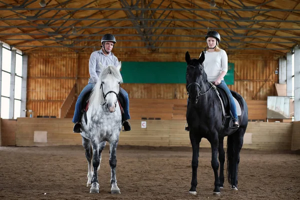 People on a horse training in a wooden arena