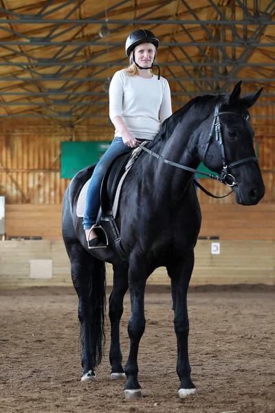 People on a horse training in a wooden arena