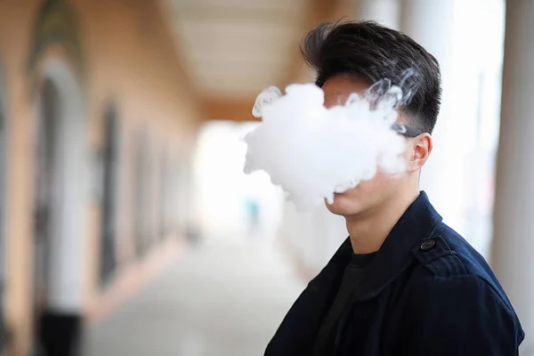 Asya genç adam sokakta Sigara — Stok fotoğraf