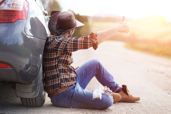 Man sitter på vägen av bilen — Stockfoto