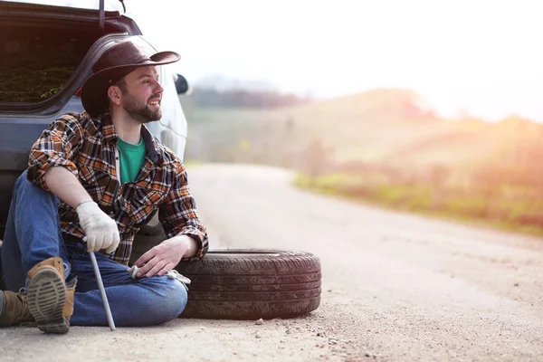 Man sitter på vägen av bilen — Stockfoto