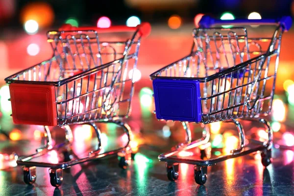 metal supermarket small cart on a background colored lights