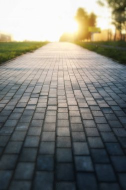 Gri kaldırım taşı yol uzakta umudu'nde Günbatımı gider.