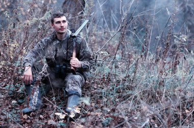 Kamuflaj ve bir sp üzerinde bir ormanda bir av tüfeği ile bir adam