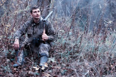 Kamuflaj ve bir sp üzerinde bir ormanda bir av tüfeği ile bir adam