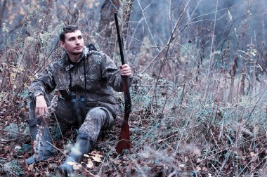 Kamuflaj ve bir sp üzerinde bir ormanda bir av tüfeği ile bir adam