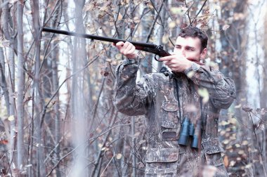 Kamuflaj ve bir sp üzerinde bir ormanda bir av tüfeği ile bir adam