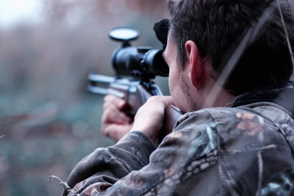 Kamuflaj ve bir sp üzerinde bir ormanda bir av tüfeği ile bir adam — Stok fotoğraf