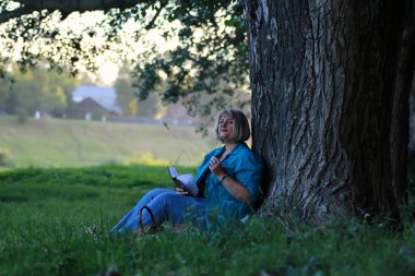 kadınla çimenlerin üzerinde kitapla Park