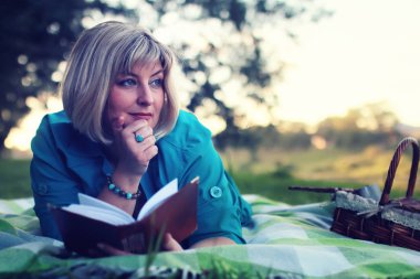 kadınla çimenlerin üzerinde kitapla Park